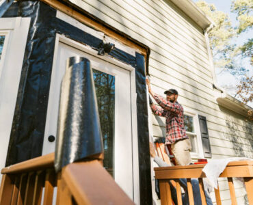 Father and son repair the siding of a colonial style house